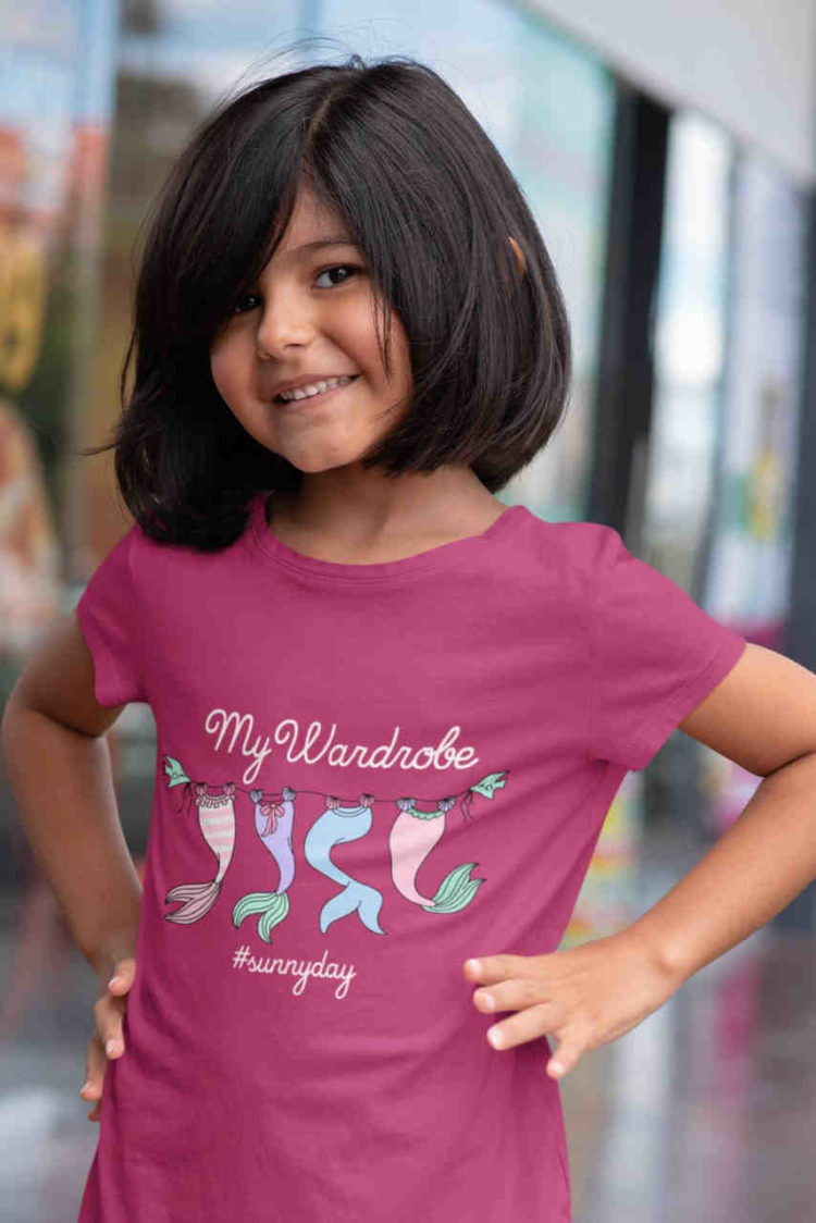 sweet girl in dark pink tshirt with Mermaid tails on clothesline