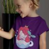 cute girl in a purple tshirt with a mermaid in a teacup