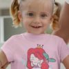 little girl in a light pink tshirt with a mermaid in a teacup