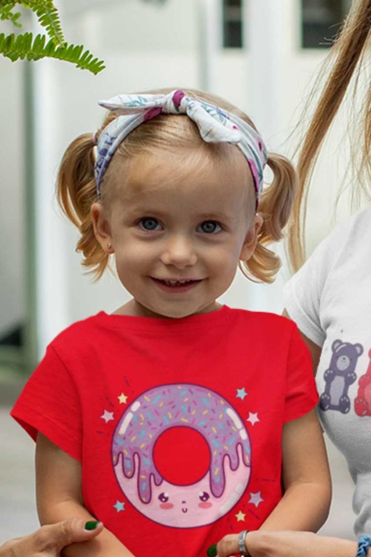 little girl in red tshirt with a pink purple smiling donut