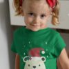 cute girl in a green tshirt with a Bear in a santa hat