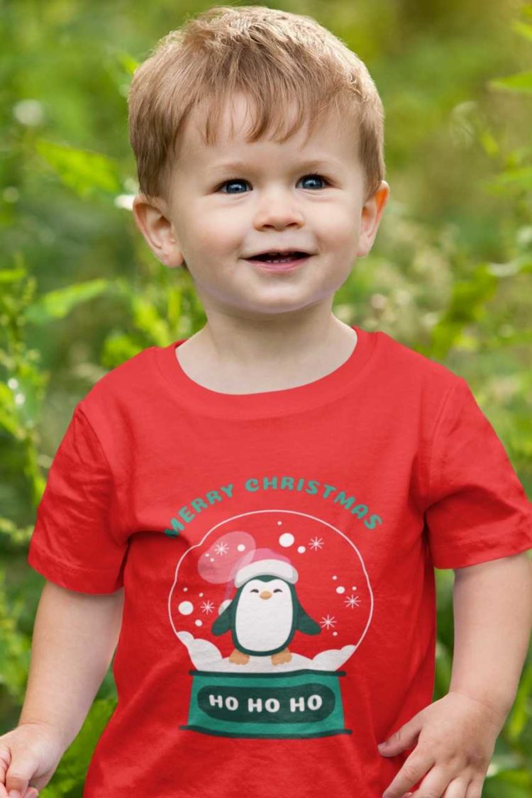 Cute boy in a Red tshirt with a penguin inside a snow globe