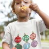 little boy blowing bubbles in a white tshirt with Christmas ornaments