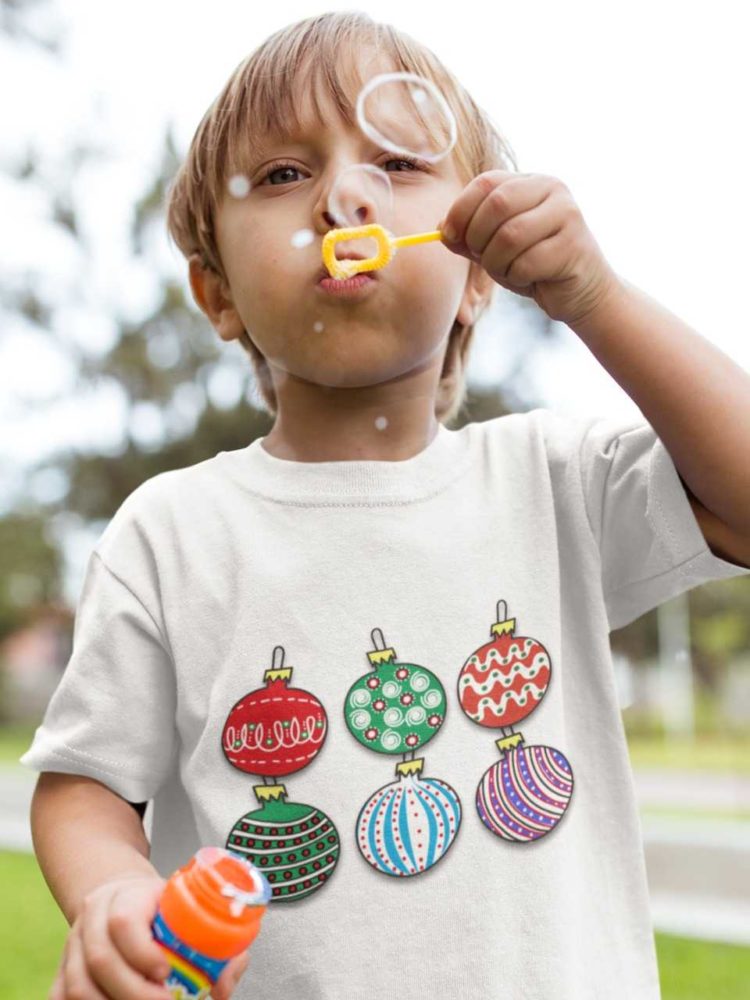 little boy blowing bubbles in a white tshirt with Christmas ornaments