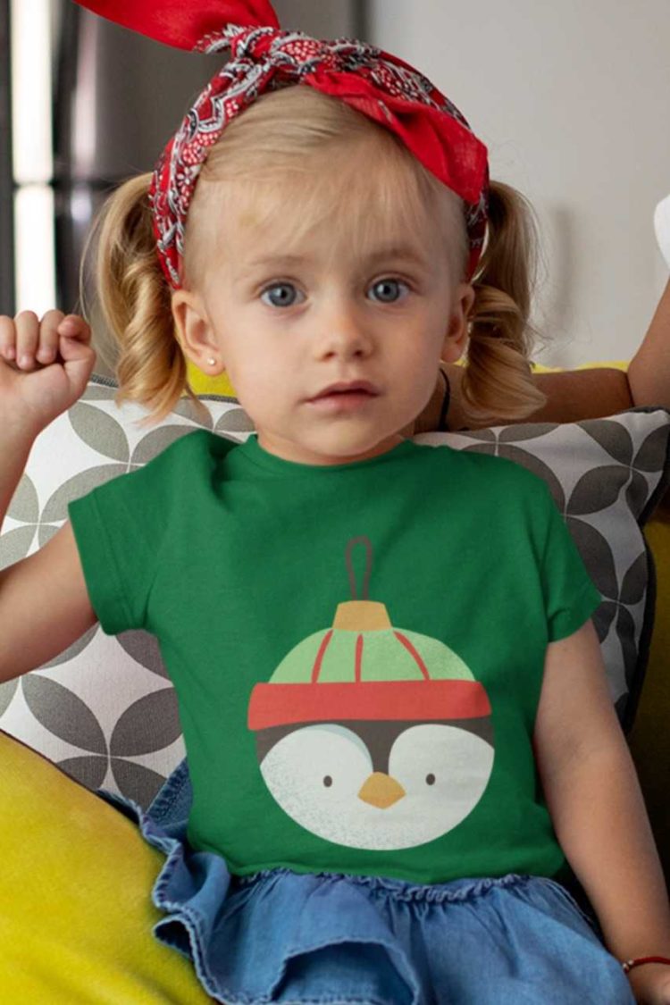 cute girl in a Green tshirt with penguin christmas ornament