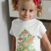 little girl in a white tshirt with a christmas tree with character ornaments