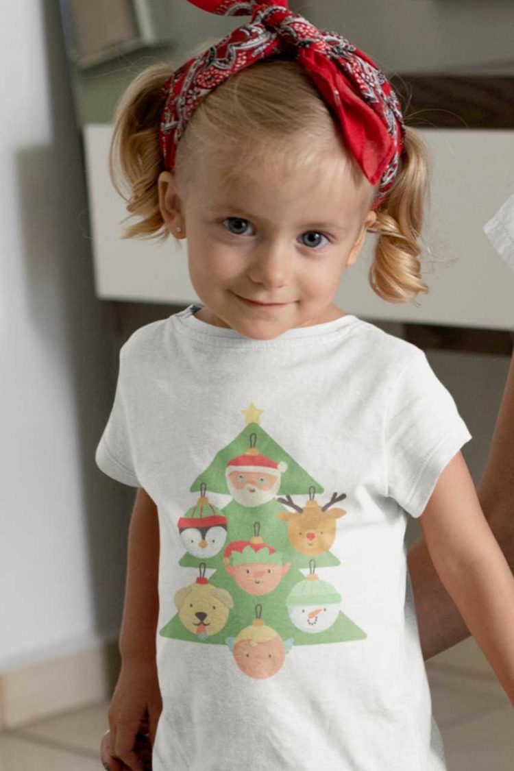 little girl in a white tshirt with a christmas tree with character ornaments