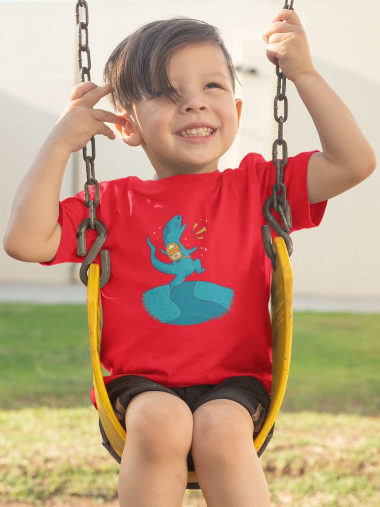 sweet boy swinging in a red tshirt with a dinosaur wearing a backpack